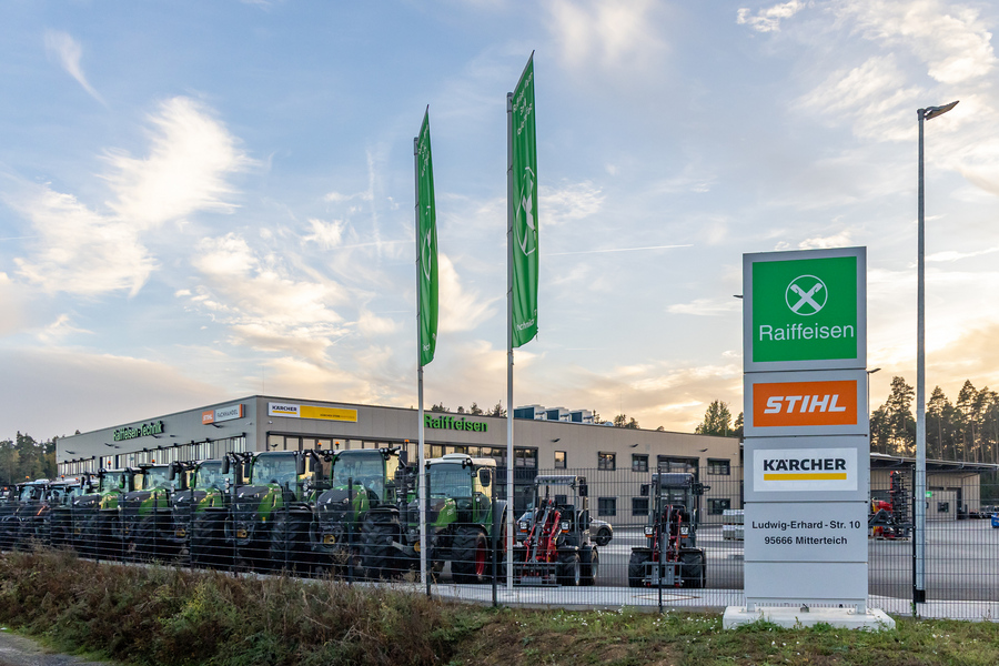 Außenansicht eines Raiffeisen-Gebäudes in Mitterteich mit mehreren Traktoren und großen Fahnen; gebaut vom Hochbau der Firma Kassecker.