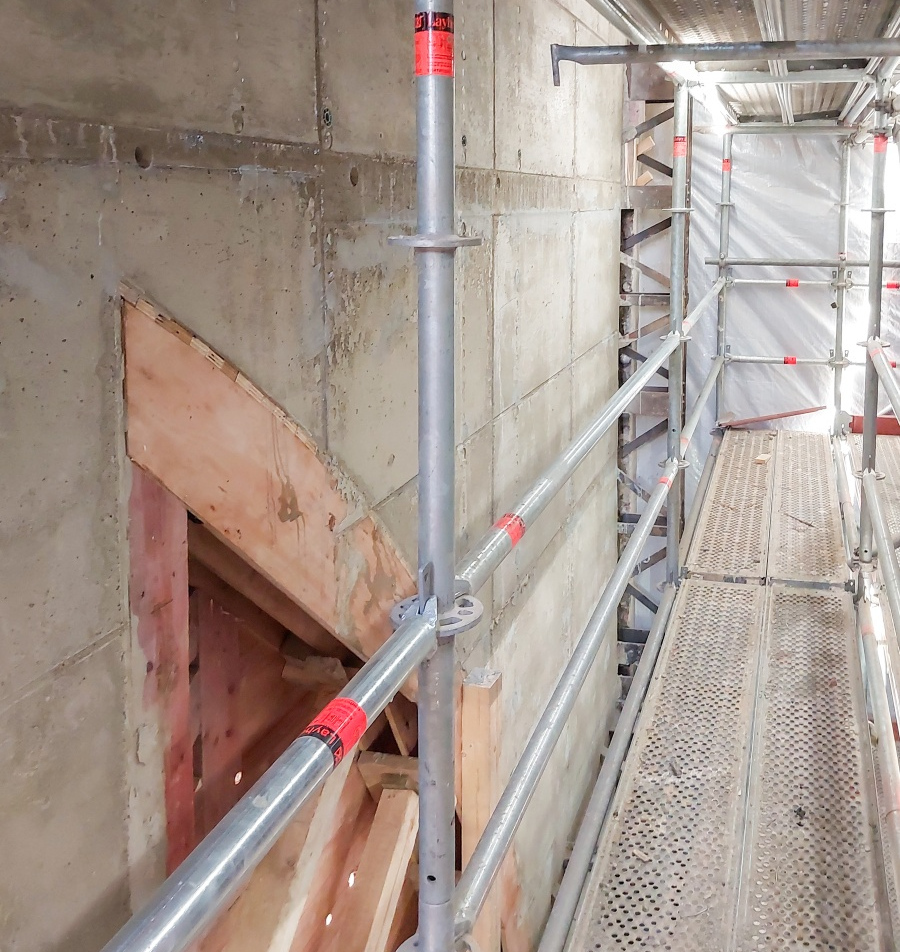 Baugerüst vor Betonwand mit Holzschalung für ein bogenförmiges Fenster